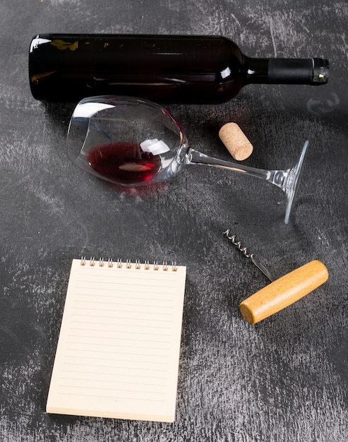 Вид сбоку красное вино с копией пространства в тетради на черном каменной вертикали