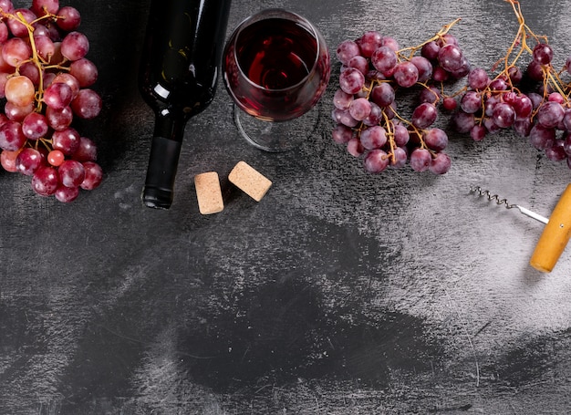 Вид сбоку красное вино с виноградом и копией пространства на черном камне по горизонтали