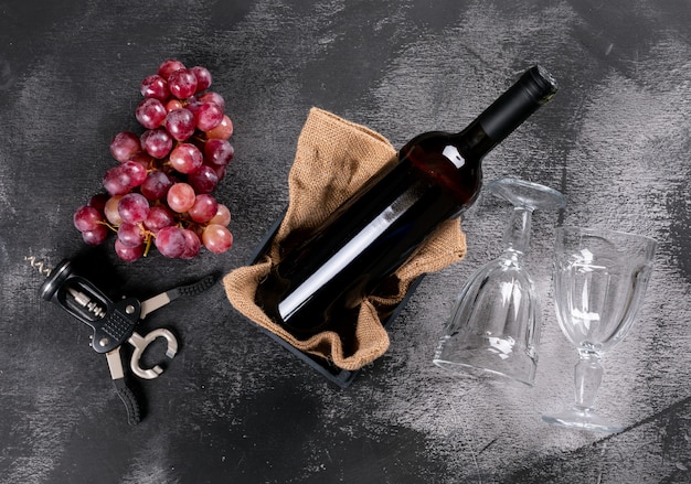 横の黒い石の荒布を着た木枠のブドウと側面図赤ワイン