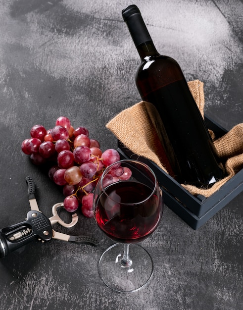 垂直の黒い石に荒布を着た木枠のブドウと側面図赤ワイン