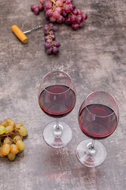 Side view red winein glasses and grape on dark stone vertical