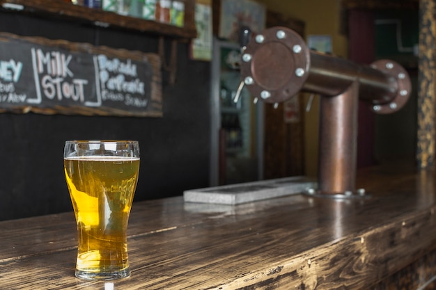 Вид сбоку освежающий стакан с пивом на столе