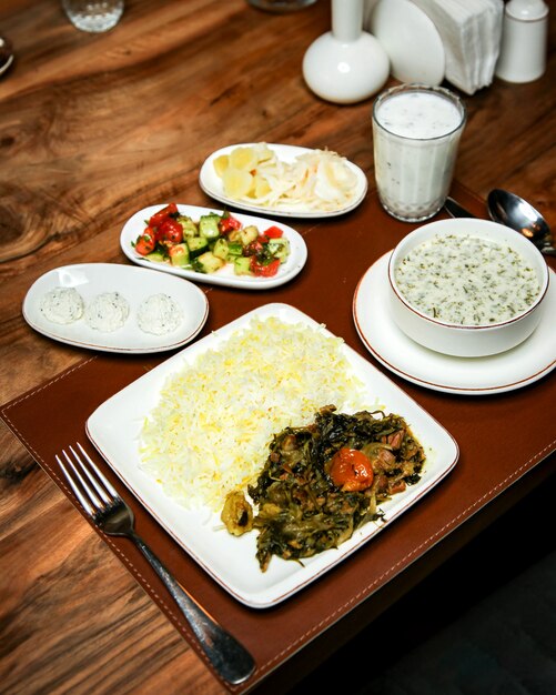 Вид сбоку риса с тушеным мясом и зеленью на деревянный стол