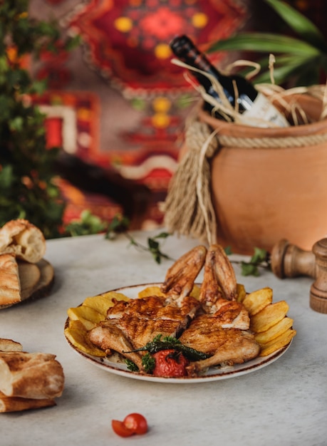 Side view of roasted chicken baked potatoes and grilled vegetables on a plate on the table