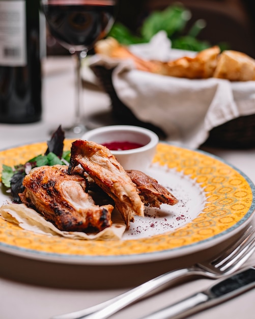 Side view of roasted chicken served with sauce on a plate