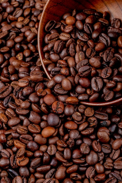 Вид сбоку жареных кофейных зерен, разбросанных от деревянной миске на кофейных зернах