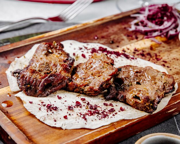 Side view of roasted meat pieces on a wooden board