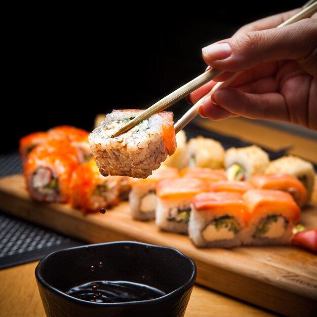 Side view roll with soy sauce and chopstick in hand