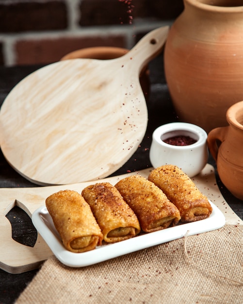 Side view rolled pancakes sprinkled with sumac on the board