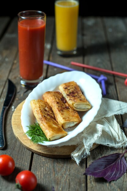 Pancake rotolati vista laterale con succo di pomodoro e pomodori