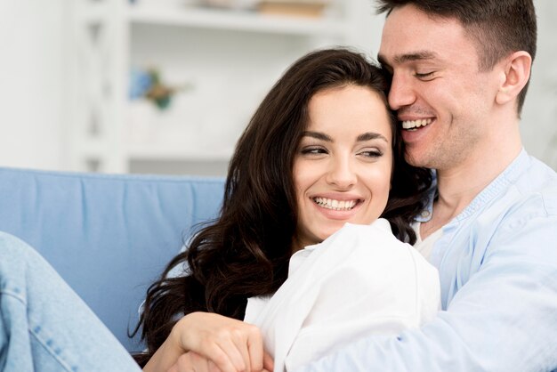 Side view of romantic and happy couple on sofa at home