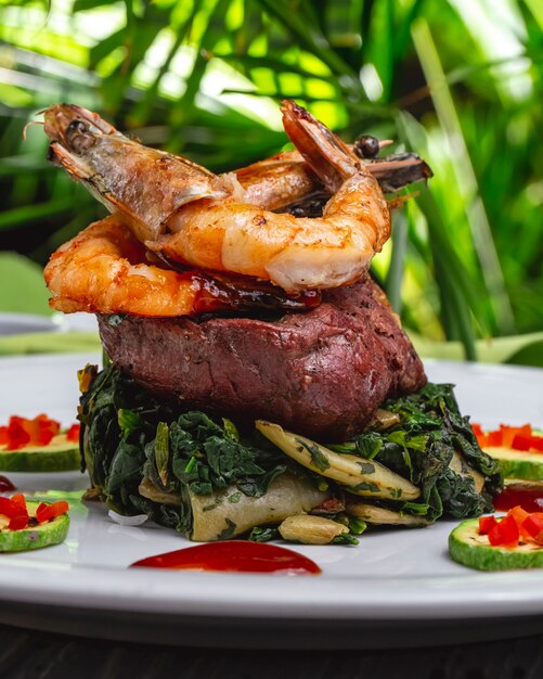Side view royal shrimps with grilled red meat spinach green beans and zukini on a plate