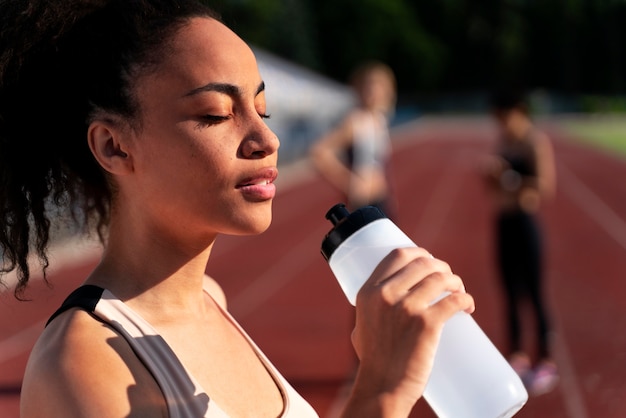 Free photo side view runner holding a bottle of water