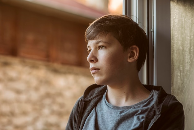 Ragazzo triste di vista laterale che osserva fuori