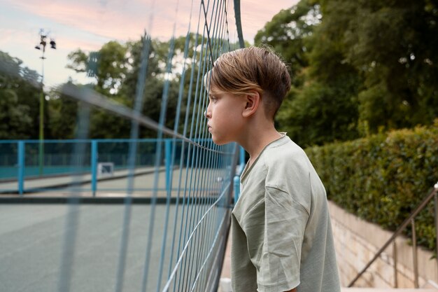 Side view sad boy near fence