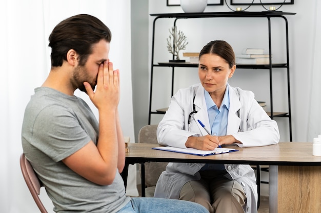 Side view sad man talking to doctor