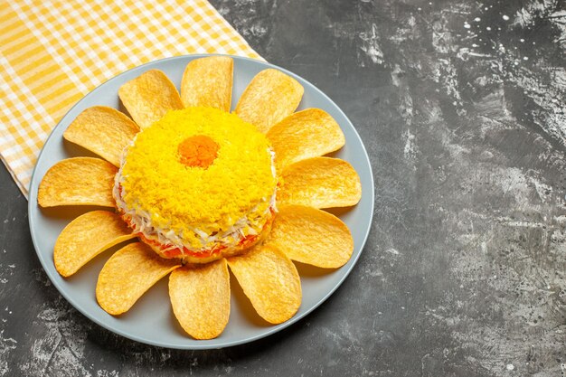 Side view of salad on the left-middle side with yellow napkin under it on dark grey background