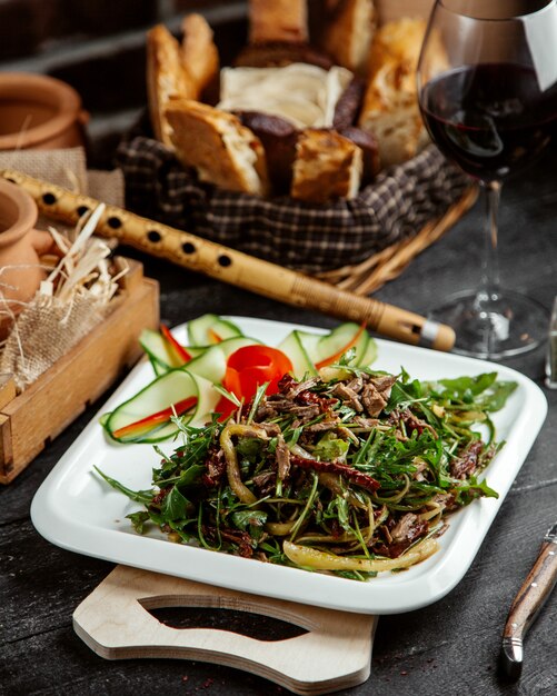 Side view salad with greens and meat with vegetables on a board with bread