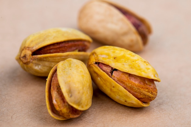 Side view of salted roasted pistachios on old paper texture background