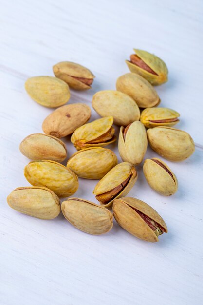 Side view of salted roasted pistachios on white background