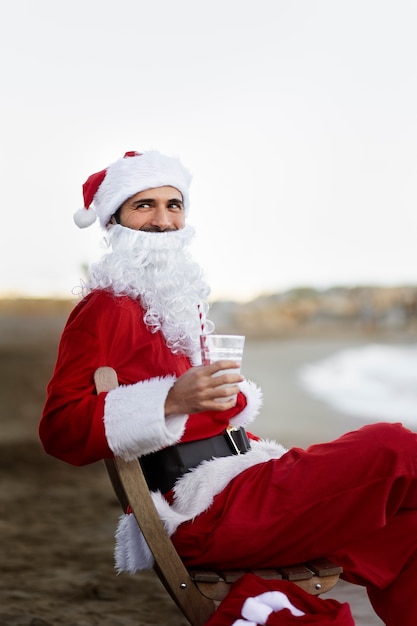 Foto gratuita babbo natale di vista laterale che si siede sulla sedia