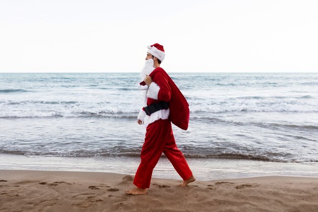 해변에서 걷는 측면보기 산타 클로스