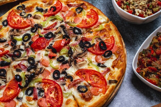 테이블에 토마토 피망 훈제 소시지 블랙 올리브와 치즈 측면보기 소시지 피자