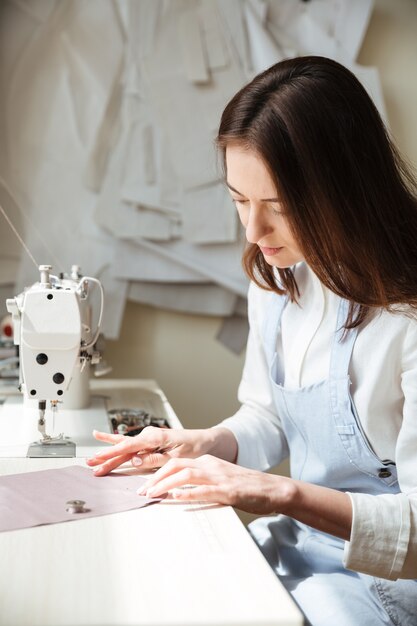 ミシンで働く女性の裁縫師の側面図