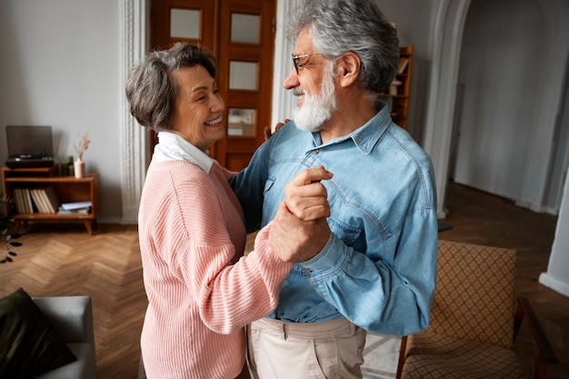 Side view senior couple dancing at home