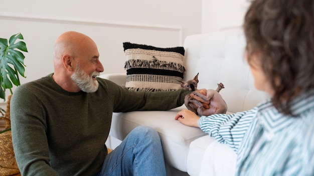 Free photo side view senior couple with cat at home