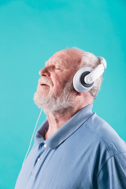 Free photo side view senior man enjoying music