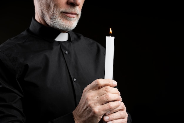 Free photo side view senior man holding lit candle