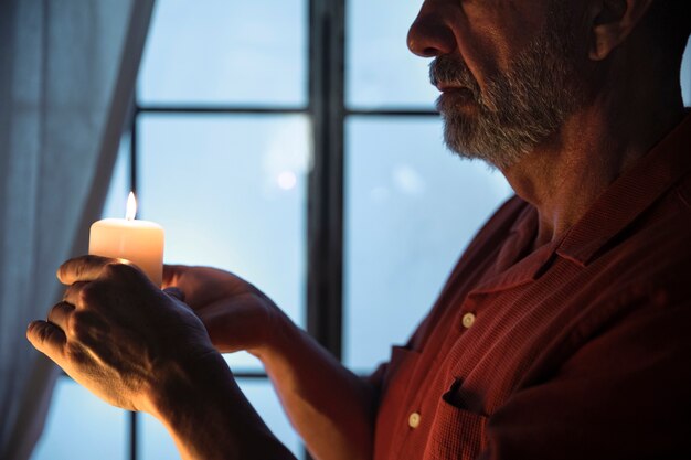 Side view senior man holding lit candle