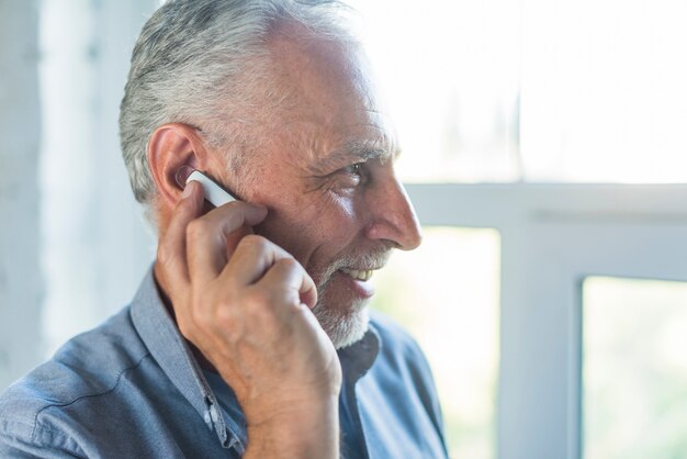 Side view of senior man talking on wireless bluetooth headset