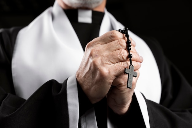 Side view senior priest holding cross