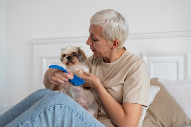 Free photo side view senior woman brushing dog