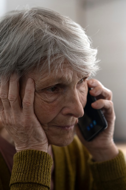 Бесплатное фото Вид сбоку пожилая женщина разговаривает по телефону