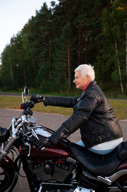 Бесплатное фото Вид сбоку пожилая женщина с мотоциклом