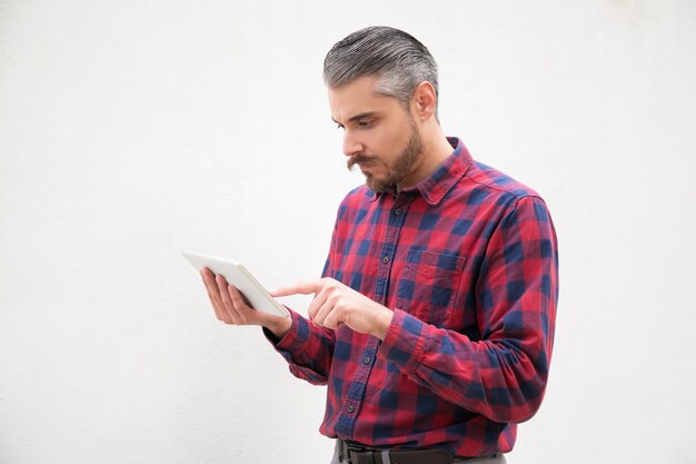 Side view of serious man using tablet pc