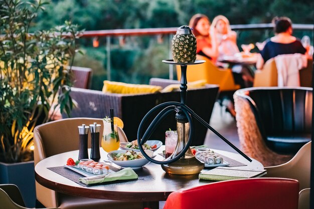 Side view served table with sushi and pineapple shisha