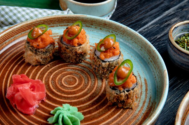 Вид сбоку набора запеченные роллы суши с васаби и имбирем на тарелке