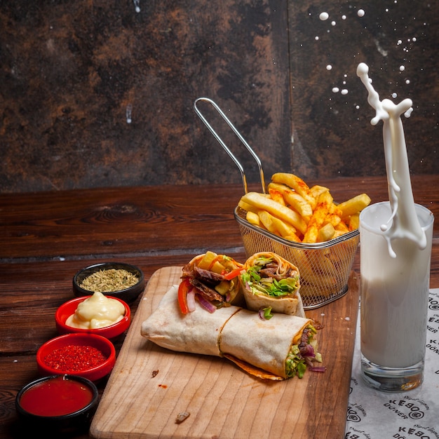 Side view shawarma with fried potatoes and ayran and splash in board cookware