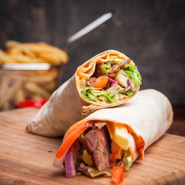 Side view shawarma with fried potatoes in board cookware