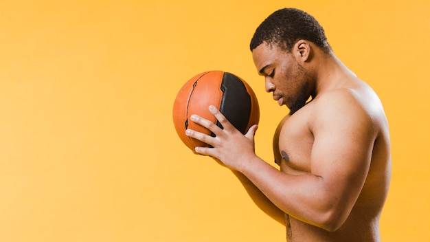 Free photo side view of shirtless athletic man holding basketball