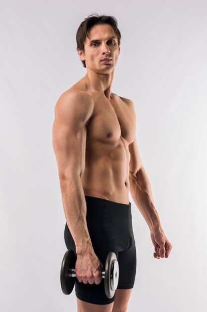 Side view of shirtless athletic man holding weight