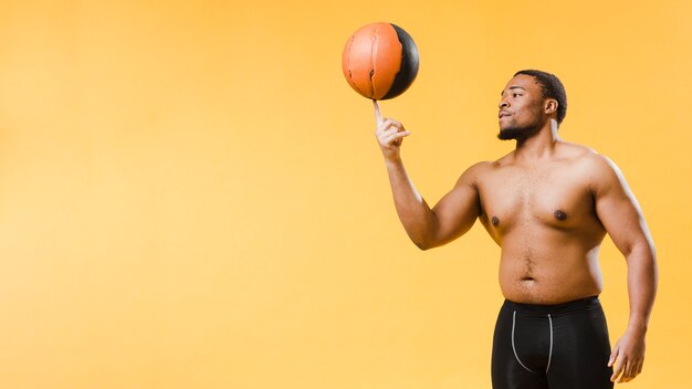 Вид сбоку без рубашки спортивного человека с баскетболом