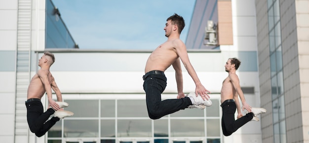 Side view of shirtless hip hop artists posing mid-air while dancing