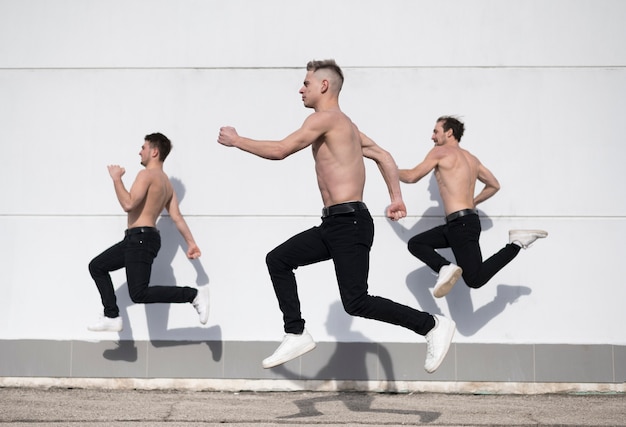 Side view of shirtless hip hop dancers in mid-air