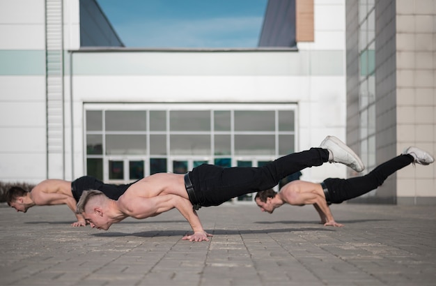 Side view of shirtless hip hop dancers outside on the ground