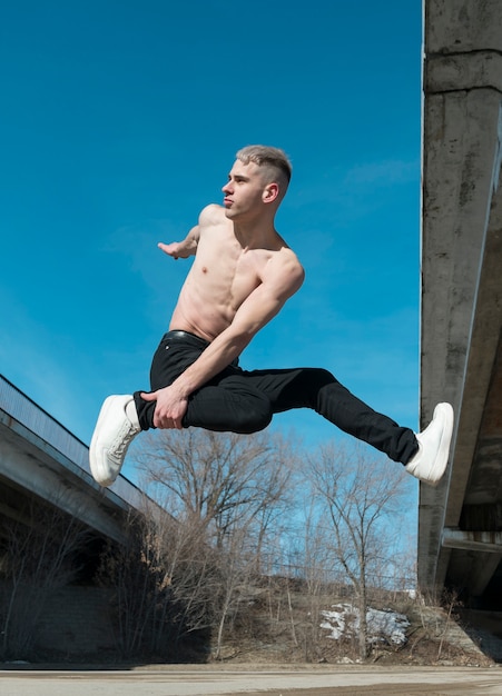 Side view of shirtless hip hop performer pose mid-air